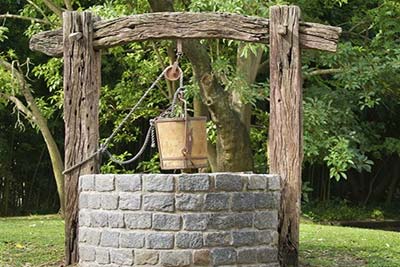 Stone well with a bucket on a rope.